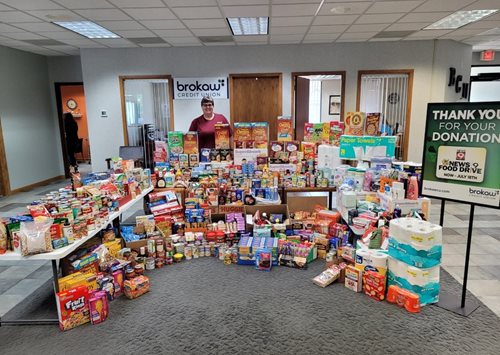 Person posing with arrangement of donated food items.