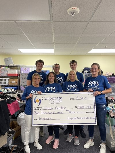 Group of volunteers holding oversized check.