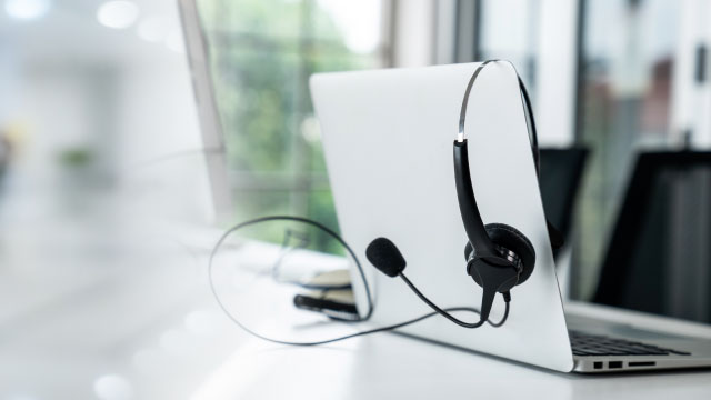 Photo of a laptop sitting on a desk with a headset.