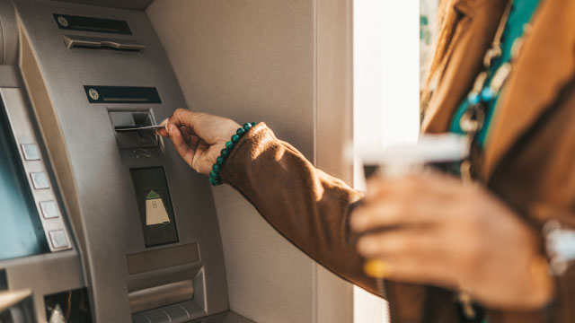 Photo of a person accessing an ATM with their debit card.