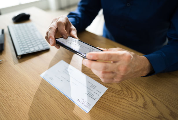 Photo of a person using their phone to take a photo of their check.